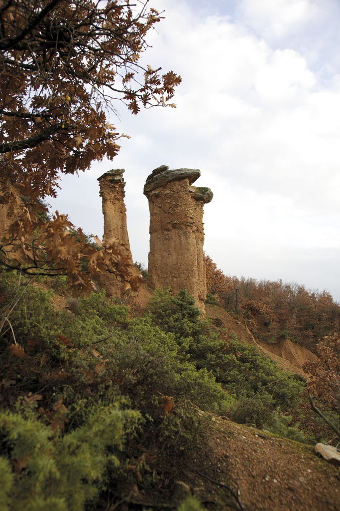 Boucharia. (Photo: Apostolos Tsolakis) Just 1 km southeast away from the village of Mikrovalto, there are some impressive formations of nature which are the result of ground erosion that began 70.000 years ago. They look like a vertical dirt piles, which consist of sand, gravels, loam, clay and some kind of adhesive materials. The top of these piles is covered by a slate rock, which functioned as a protection umbrella in the evolution of the formation.
